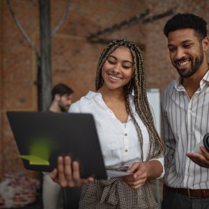 Cheerful young businesspeople with tablet working in office, a cooperation concept.